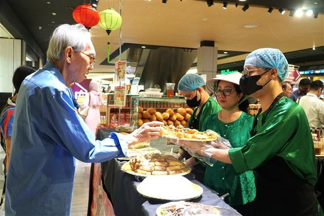 Un Malaisien déguste le sandwich vietnamien. Photo: VNA vna-potal-khai-mac-tuan-le-hang-viet-nam-tai-malaysia-8013734.jpg