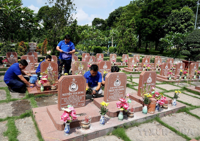 Des membres de l'Union de la jeunesse communiste Hô Chi Minh prennent soin des tombes des héros et des martyrs au cimetière des martyrs de Hô-Chi-Minh-Ville. Photo : VNA anh-2.jpg
