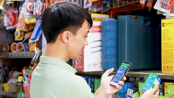 Un propriétaire d'une boutique utilise l'application de gestion des ventes. Photo: tuoitre.vn base64-1745770106238689850312.jpg
