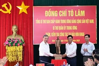 Le secrétaire général du Parti To Lam (gauche) offre une statue de l'Oncle Hô à des responsables de la commune de Dat Mui, province de Ca Mau. Photo : VNA