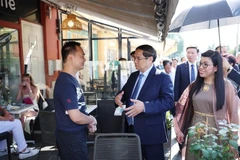 Le Premier ministre Pham Minh Chinh et son épouse rencontrent des commerçants dans le Vieux Nice. Photo : VNA