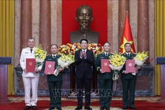 Le président Luong Cuong remet les décisions de promotion au grade de général de corps d’armée à quatre officiers supérieurs de l’Armée et de la Police populaires du Vietnam. Photo : VNA