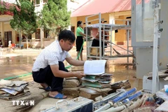Hoang Huu Duong, directeur du lycée de la commune de Yen Binh, province de Lang Son au Nord, examine les documents et supports pédagogiques encore utilisables et s'efforcera de les exploiter. Photo : VNA