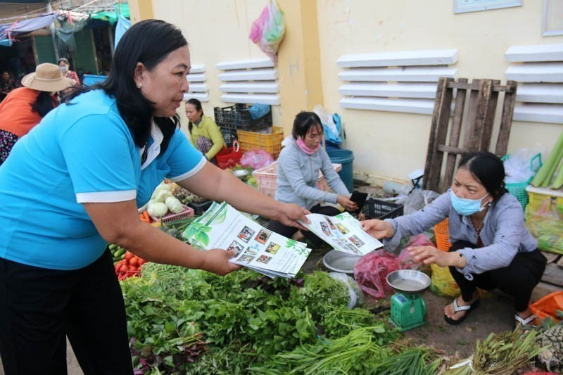 Distribution de dépliants appelant les visiteurs et vendeurs du marché de Tam Thanh, province de Binh Thuân (Centre), à la participation à la protection de l'environnement et à la lutte contre les déchets plastiques. Photo : VNA