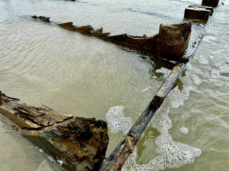 La carcasse en bois du navire fait saillie à même le sable, mise au jour par l'érosion. Photo: VNA