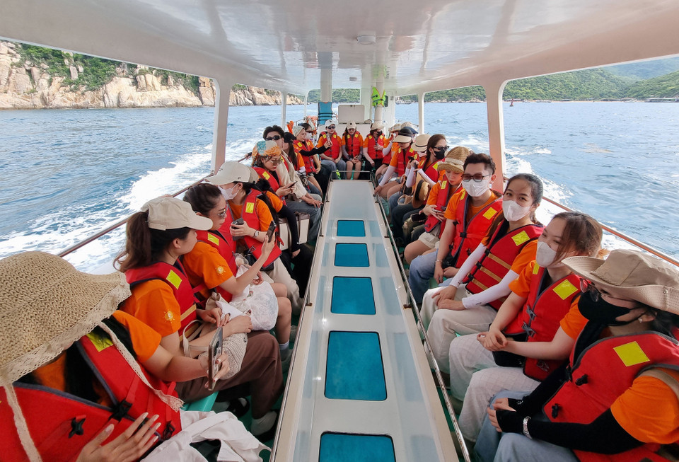 Les touristes prennent un bateau à fond de verre pour découvrir la baie de Vinh Hy. Photo : VNA