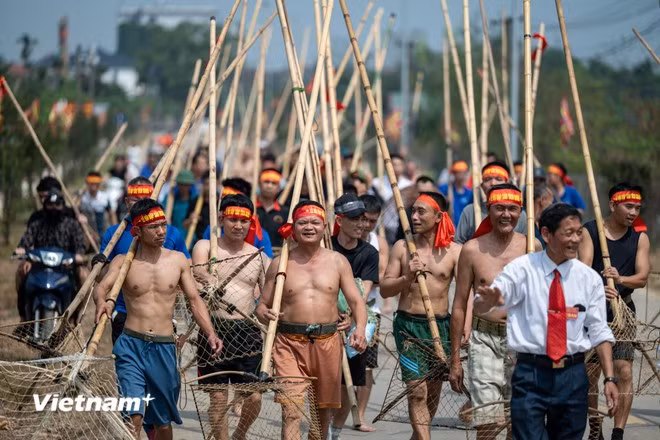 En cette période, les visiteurs peuvent aisément observer des centaines de jeunes hommes torse nu, avançant dans l’eau, maniant de longues perches en bambou qu’ils frappent vigoureusement à la surface de la rivière. Le bruit rythmé des perches, les bancs de poissons dispersés et les cris d’encouragement composent une atmosphère à la fois festive et animée. Photo: VietnamPlus