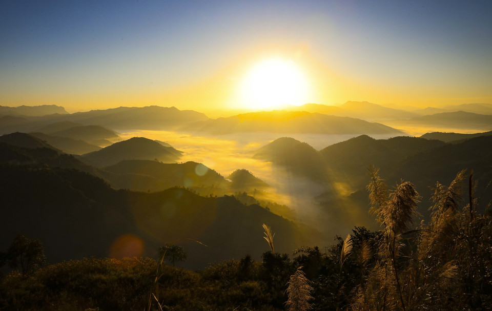 La lumière du soleil traverse les nuages qui flottent entre les montagnes et les collines. Photo : VNA