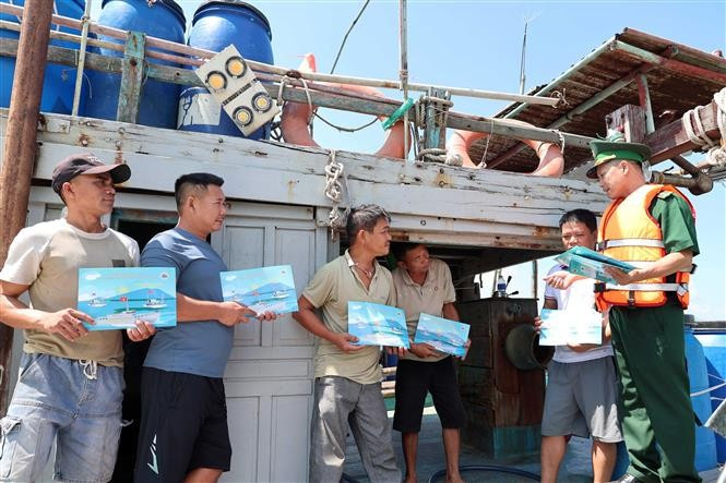 Des officiers et soldats du poste de garde-frontière de Son Tra (Commandement de la Garde-frontière de la ville de Da Nang) diffusent des informations sur la pêche INN aux pêcheurs des bateaux de pêche d'autres provinces qui mouillent à l'embouchure de la ville pour éviter les tempêtes. Photo : VNA