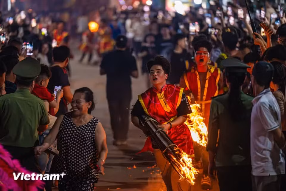 Lorsque le cortège approche de la maison communale, des dizaines de porteurs tenant des torches courent en tête pour ouvrir le passage. Photo : Vietnam+