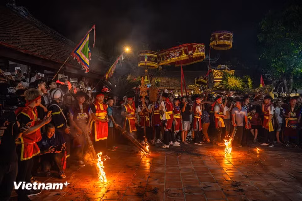 Sous la lumière rougeoyante des torches, les spectateurs affluent nombreux. Beaucoup cherchent à passer sous le palanquin afin de recevoir bénédictions, prospérité et chance. Photo : Vietnam+