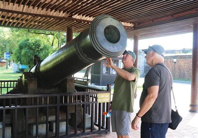 Des touristes étrangers découvrent un ancien canon dans la citadelle de Hue. Photo: VNA