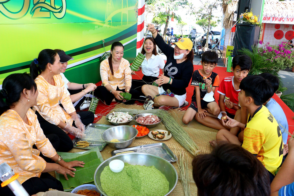 Des touristes et des habitants locaux participent à la confection traditionnelle du gâteau de riz gluant vietnamien. Photo : VNA