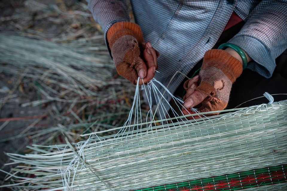 Les artisans fixent avec soin des fils de nylon blancs autour des bords de chaque natte. Photo : VNA