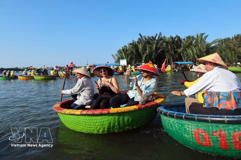 Des touristes internationaux découvrent le savoir-faire traditionnel des habitants de Cam Thanh, classé parmi les 50 plus beaux villages du monde, en s'essayant à la technique du « secouage du panier ». Photo : VNA