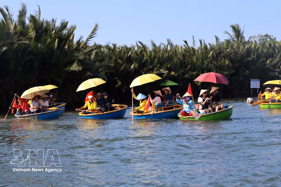 Des touristes internationaux apprécient l’expérience unique d’une promenade en barque en forme de panier à Cam Thanh. Photo : VNA