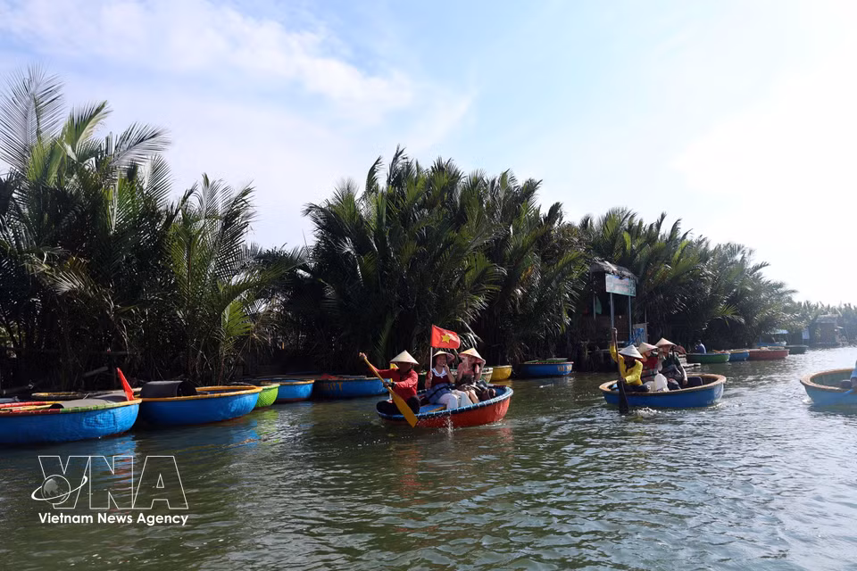 Des visiteurs glissent sur l’eau à bord de barques rondes traditionnelles. Photo : VNA