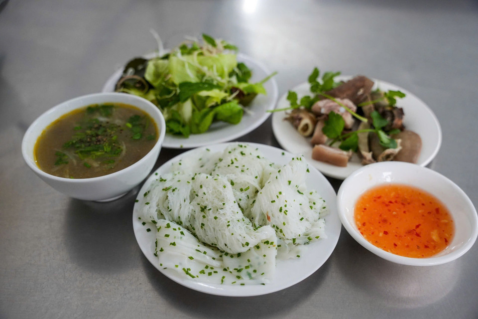 Les nouilles de riz idéales se distinguent par des brins fins et élastiques qui ne s'émiettent pas. Leur goût unique provient de l'équilibre entre la farine de riz et la richesse de l'huile de coco. Elles se dégustent traditionnellement accompagnées d'abats de porc (cœur, foie, rognons), d'herbes aromatiques et d'une sauce de poisson au tamarin pour un contraste de saveurs parfait. Photo : VNA