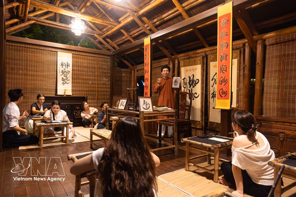 Des touristes vietnamiens et étrangers participent à un cours de calligraphie, dans le cadre de la visite nocturne "L’Essence du Taoïsme" au Temple de la Littérature.