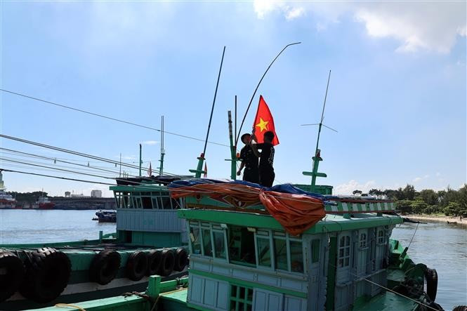 Des officiers et soldats du poste de garde-frontière de Son Tra (Commandement de la Garde-frontière de la ville de Da Nang) offrent un drapeau national à un navire de pêche. Photo : VNA