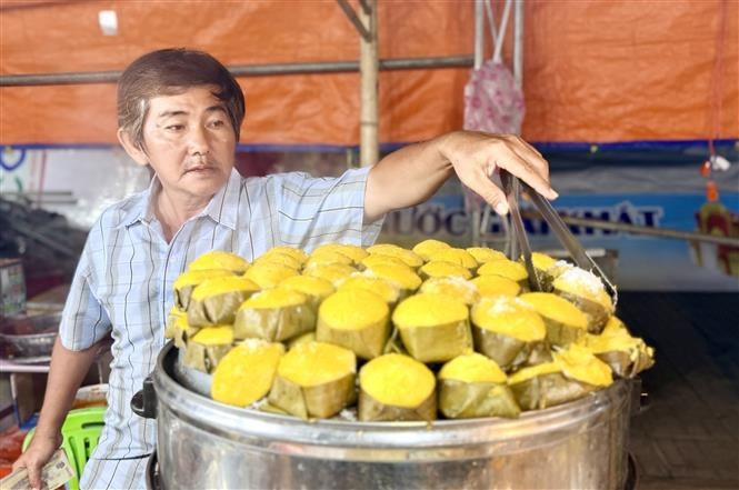 Un artisan de gâteaux traditionnels d'An Giang à côté d'un pot de gâteaux de feuilles de palmier cuits à la vapeur, parfumés et fleuris. Photo : VNA