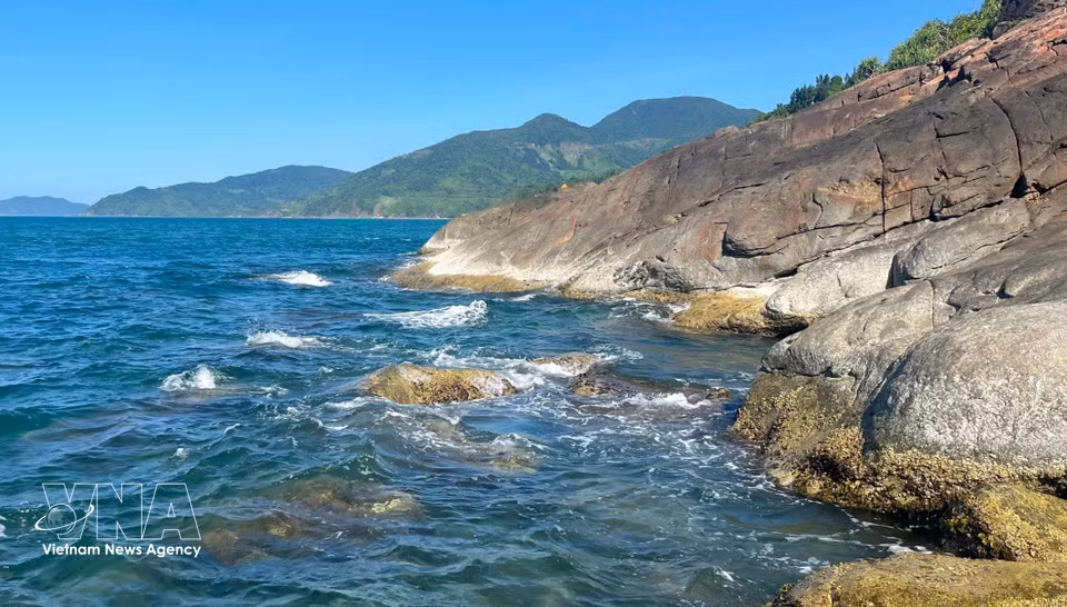 Le relief escarpé du col de Hai Van se prolonge jusqu'au rivage, où de massifs blocs de pierre contrastent avec les eaux limpides de la baie de Lang Co.