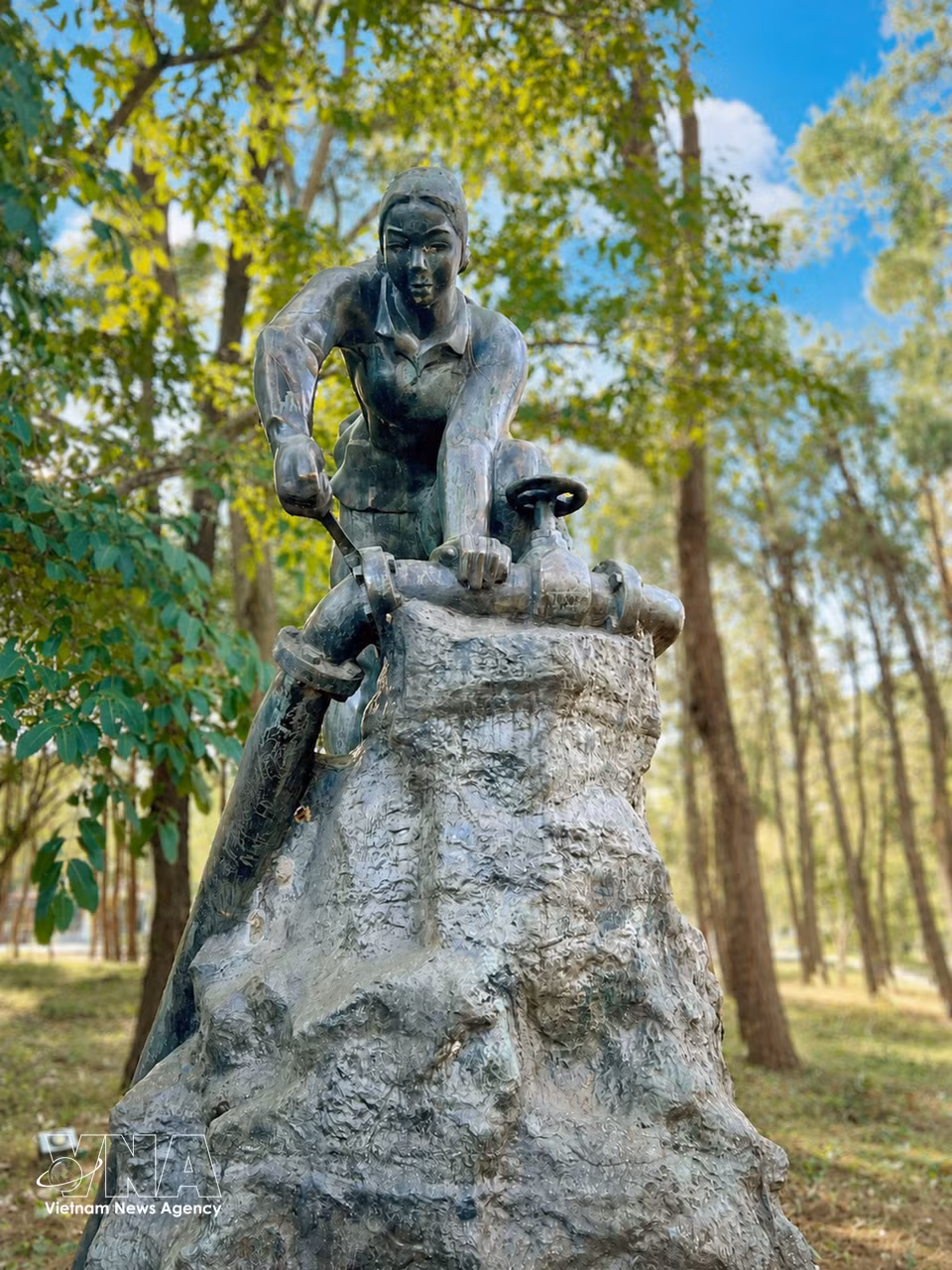 La statue en bronze du parc mémorial du Cimetière national des martyrs de Truong Son représente une jeune femme réparant un oléoduc au milieu du champ de bataille, évoquant les contributions et les sacrifices des forces logistiques sur la légendaire piste de Truong Son.