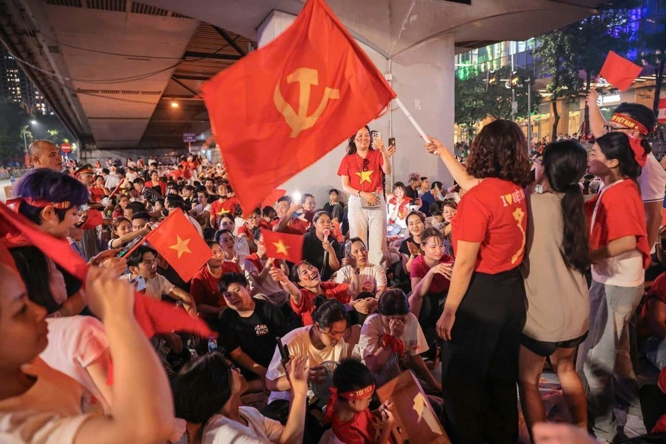 Les gens, avec les drapeaux rouges, attendent ensemble le défilé militaire et populaire célébrant le 80e anniversaire de la Fête nationale. Photo : Khanh Hoa/VNA