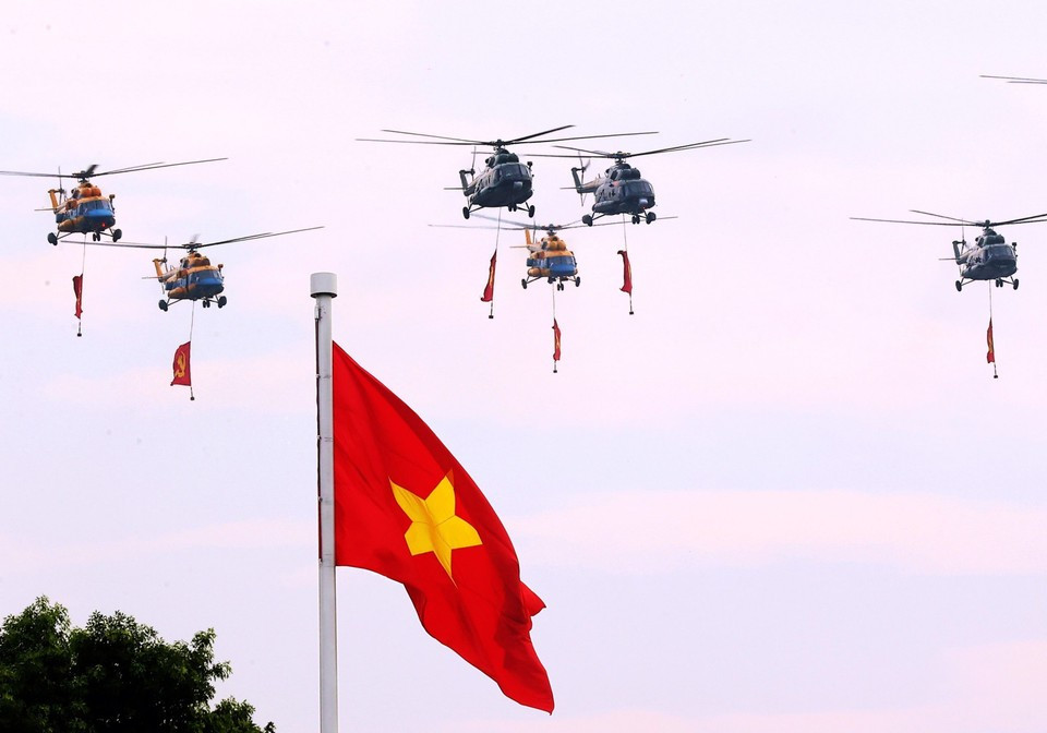 Des hélicoptères de l'Armée de l'air populaire vietnamienne portant les drapeaux du Parti et de l'État survolent le ciel de Hanoï. Photo : Thanh Tung - VNA