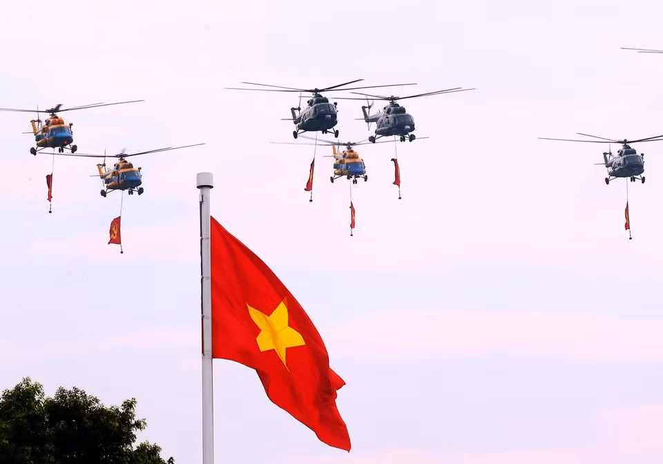 Des hélicoptères de l'Armée de l'air populaire vietnamienne portant les drapeaux du Parti et de l'État survolent le ciel de Hanoï. Photo : Thanh Tung - VNA