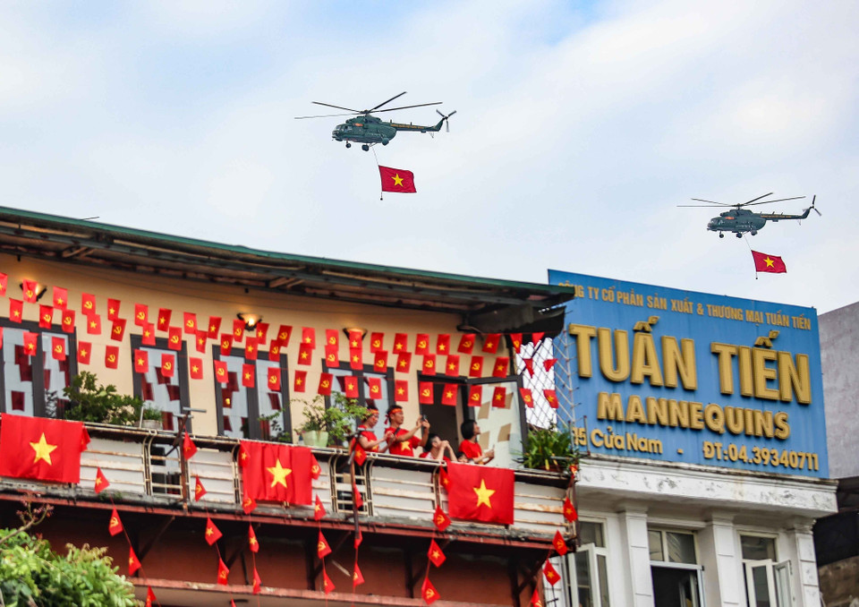 Des hélicoptères de l'Armée de l'air populaire portant le drapeau du Parti et le drapeau national survolent dans le ciel de la capitale Photo : VNA