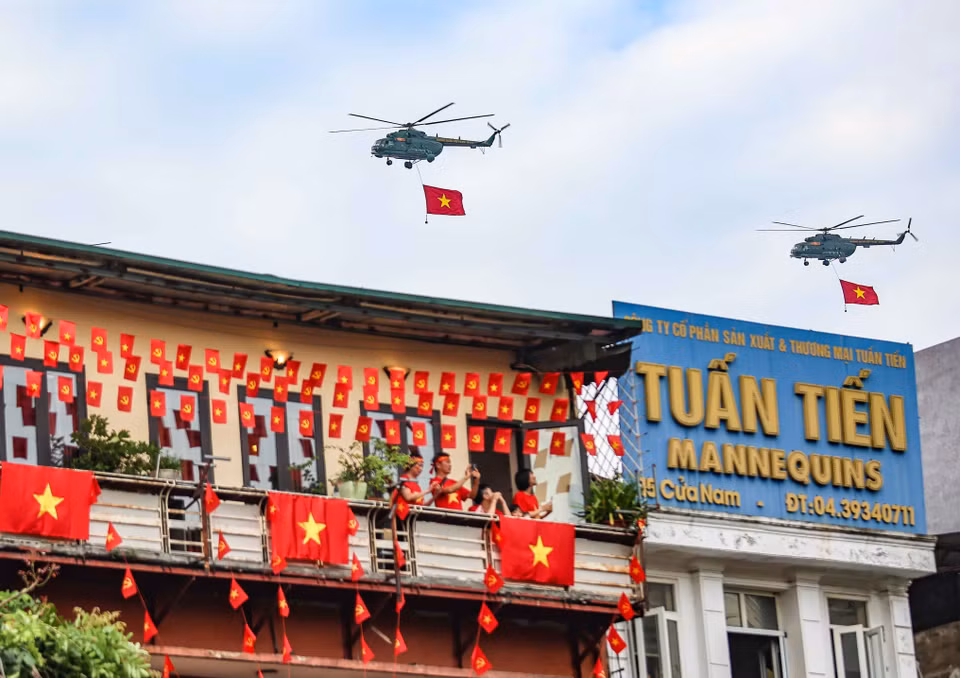 Des hélicoptères de l'Armée de l'air populaire portant le drapeau du Parti et le drapeau national survolent dans le ciel de la capitale Photo : VNA