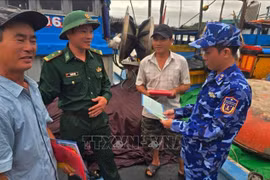 Des officiers de la Région 2 de la Garde-côtière distribuent des dépliants d’information aux pêcheurs. Photo : VNA