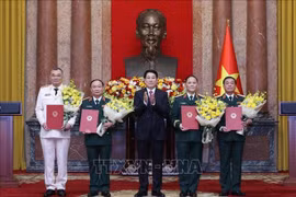 Le président Luong Cuong remet les décisions de promotion au grade de général de corps d’armée à quatre officiers supérieurs de l’Armée et de la Police populaires du Vietnam. Photo : VNA