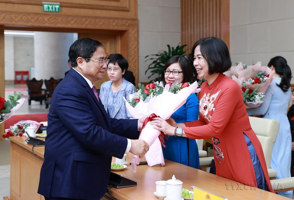 Le Premier ministre Pham Minh Chinh offre un bouquet de fleurs pour féliciter la directrice générale de l'Agence vietnamienne d'Information (VNA) Vu Viet Trang et la directrice générale adjointe de la VNA Doan Thi Tuyet Nhung lors de la réunion avec les représentantes des femmes dirigeantes et gestionnaires des agences centrales. Photo: VNA