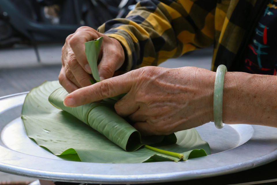 Le produit fini doit être obligatoirement enveloppé afin qu’il ne sèche pas et ne perde pas sa couleur verte. Le parfum du côm et celui des feuilles de lotus fraîches se marient bien, donnant une saveur particulière au côm de Hanoï. Photo : VNA
