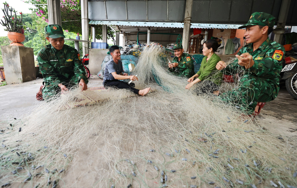 Des garde-frontières de Con Co aident les pêcheurs à ravauder leurs filets. Photo : Minh Duc/VNA