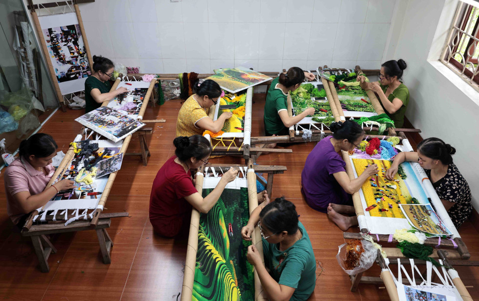 Les artisans de l'atelier de broderie Duc Ton dans la rue Tía, commune de Thang Loi, travaillent avec diligence sur des tableaux de paysages.