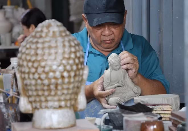 L'artisan Le Thanh Nhan produit des céramiques de Bien Hoa depuis plus de 30 ans. Il est en train de créer une statue de Bouddha en céramique. Photo : VNA