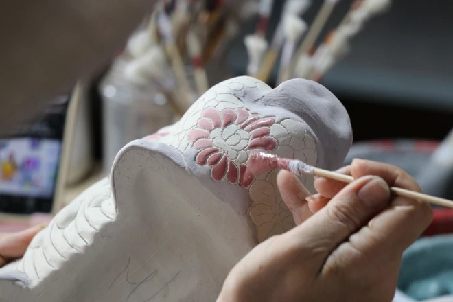 Un artisan en train de dessiner des motifs sur les produits en céramique au four de Phong Son. Photo : VNA