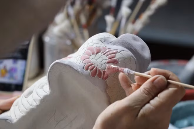 Un artisan en train de dessiner des motifs sur les produits en céramique au four de Phong Son. Photo : VNA