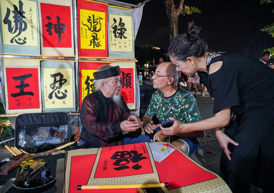 Touristes étrangers demandent des lettres dans la rue piétonne autour du lac Hoan Kiem. Photo : VNA