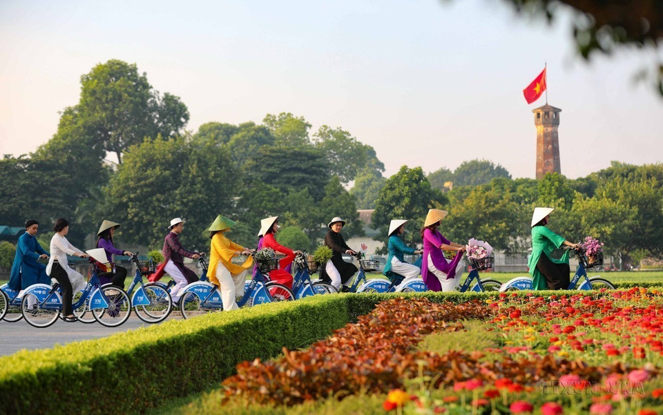 Des femmes de la capitale font du vélo dans la rue Dien Bien Phu, traversant la Tour du drapeau de Hanoï, dans le cadre du programme "Ao dai connectant le tourisme au patrimoine à Hanoï 2023". Photo : Tuan Duc – VNA