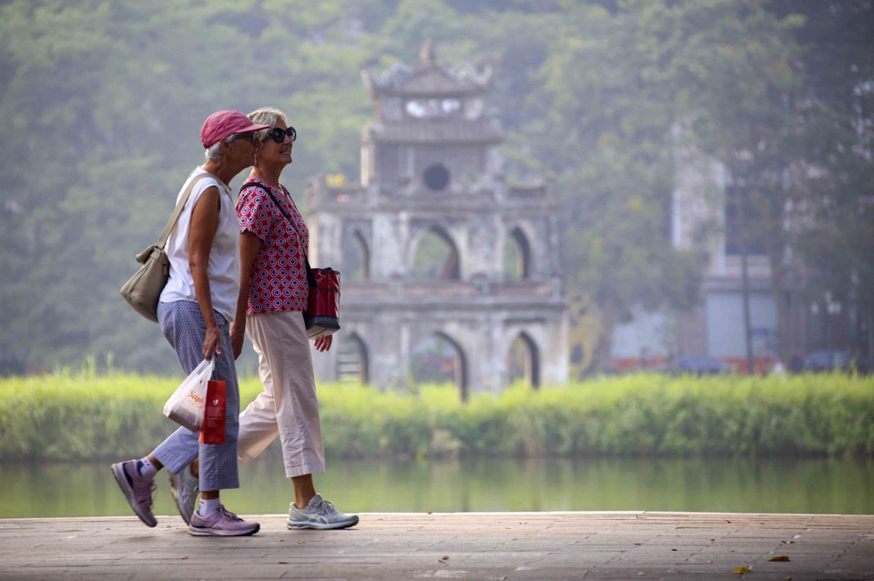 Touristes étrangers se promenant au bord du lac Hoan Kiem. Photo : VNA