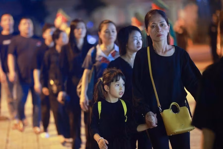 Un petit enfants et ses proches viennent rendre hommage au secrétaire général Nguyen Phu Trong. Photo : VNA