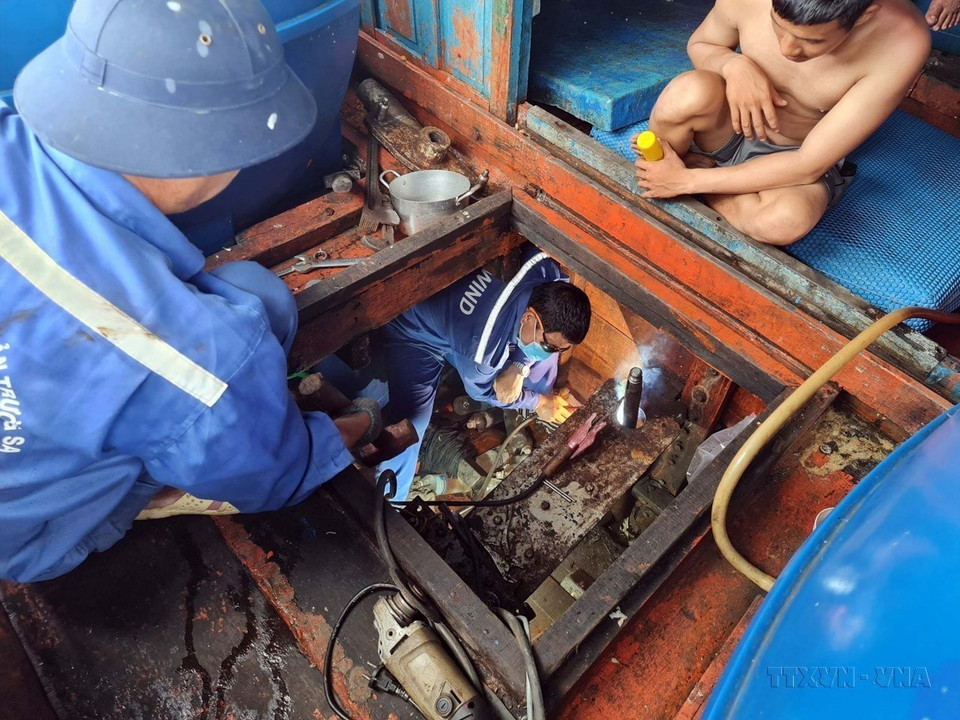 Des soldats du Centre de services logistiques et techniques de l’île de Sinh Ton, relevant de l'escadron 129, réparent le bateau de pêche QNg 96279 TS de la province de Quang Ngai. Photo: VNA