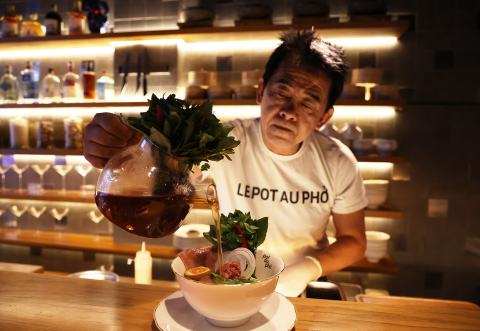 Le chef de cuisine Peter Cuong Franklin, propriétaire du Pot Au Pho, prépare un bouillon dans un bol spécial de pho. Photo : VNA