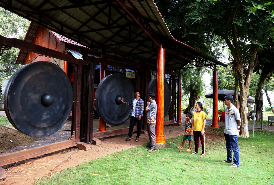 Des touristes découvrent le plus grand ensemble de gongs du Vietnam exposé dans la zone de conservation culturelle ethnique S'tieng du hameau de Bom Bo. Photo : Hong Dat – VNA
