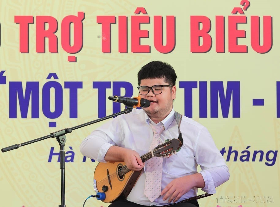 Bui Ngoc Thinh, non-voyant originaire de la province de Khanh Hoa, qui maîtrise 14 instruments musicaux et lauréat de multiples distinctions, s'exprime lors d’une conférence louant les personnes en situation de handicap, les orphelins et les mécènes exemplaires, dans le cadre du programme "Un cœur - Un monde" (Mot trai tim – Mot the gioi). Photo : VNA