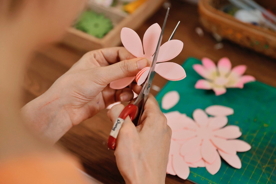Avec minutie et précision à chaque étape, les artisans créent des fleurs colorées et vibrantes. Photo: VNA